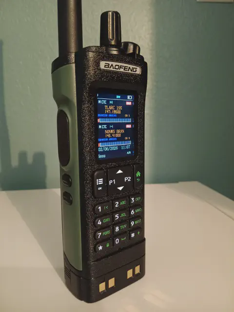 baofeng btech dm 32 front left angled view with black antenna attached green smooth side black textured body two control knobs lcd display control buttons numeric keypad