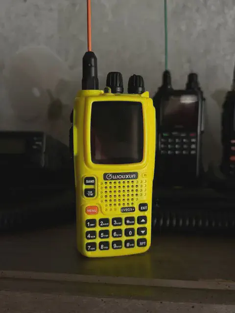 wouxun kg uv9gx front view with orange signal stick antenna attached yellow textured body two control knobs lcd display speaker grille numeric keypad control buttons